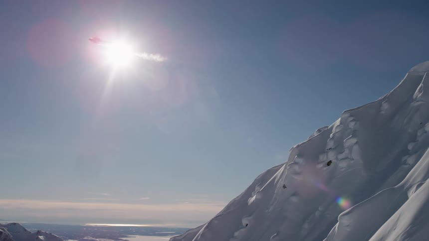A helicopter flies over a snow covered mountain