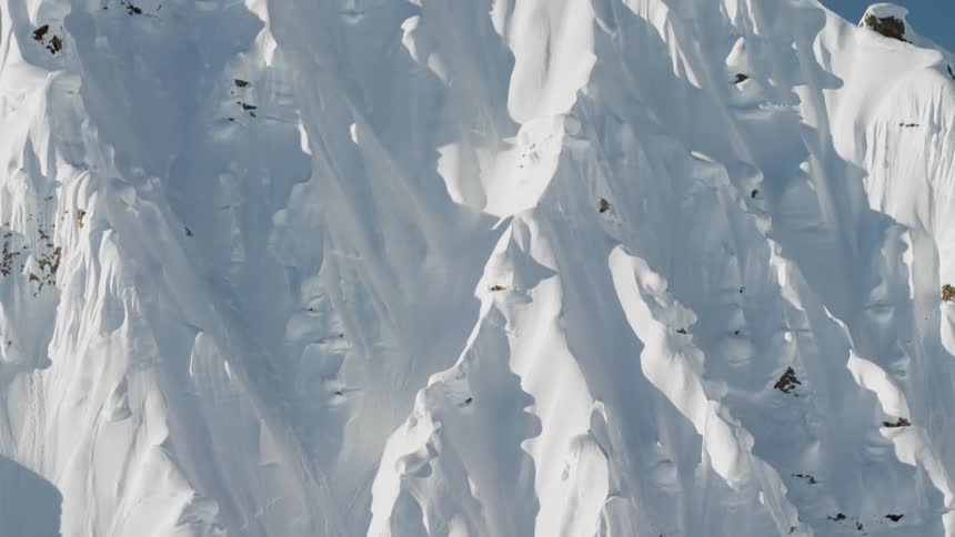 Two climbers stand atop a snow covered mountain peak