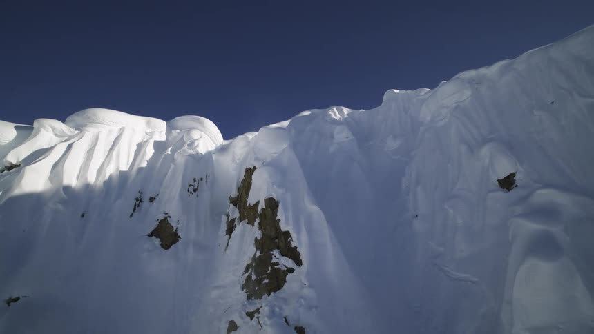 Deep snow covers nearly all of a steep mountain