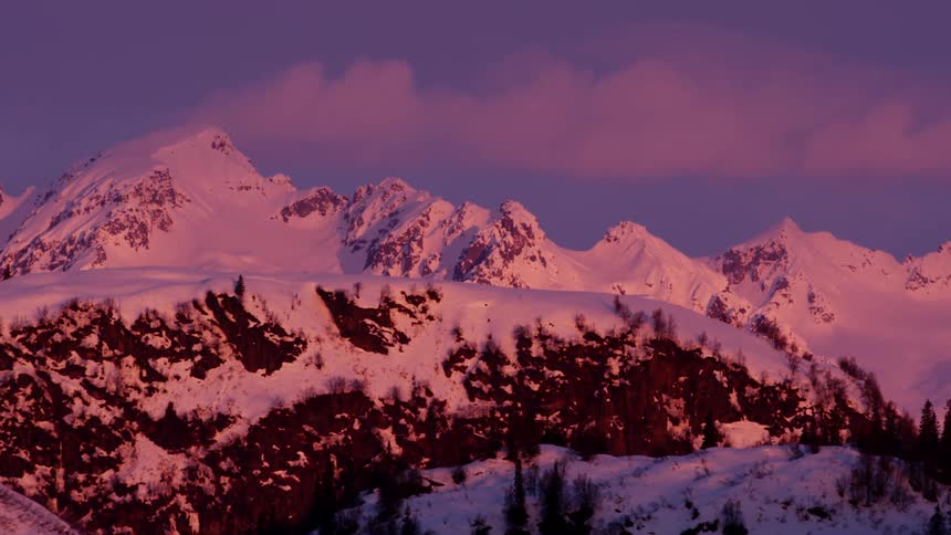 Snow covered peaks on a mountain range at sunset