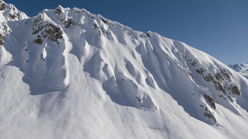 A mountain range covered in snow with the sky in the background