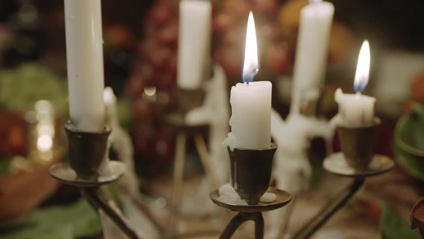 Candles burning on a candelabra sitting on a table with food
