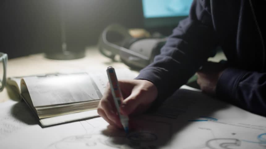 A worker in an office draws a diagram of a helmet on a piece of paper with a marker