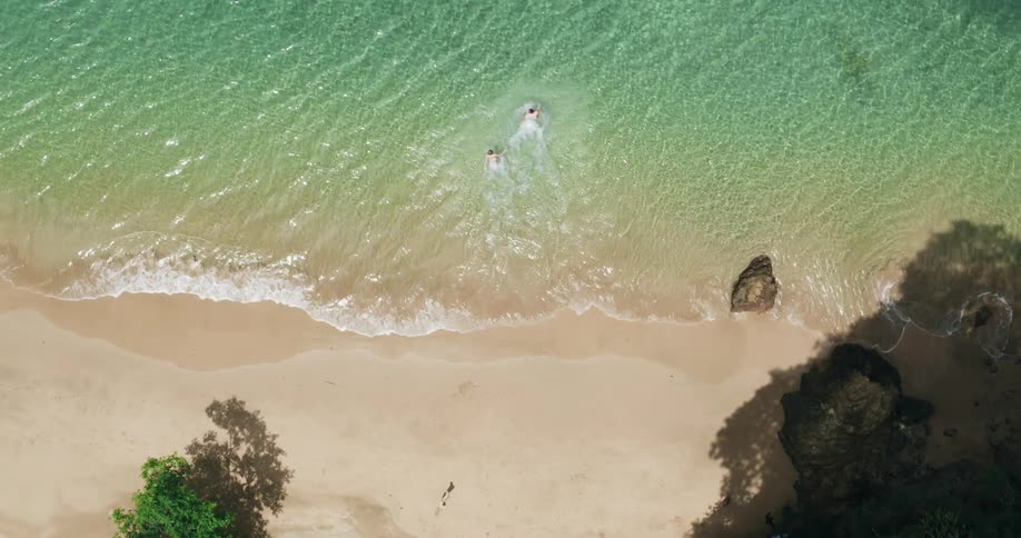 People running and splashing into tropical ocean