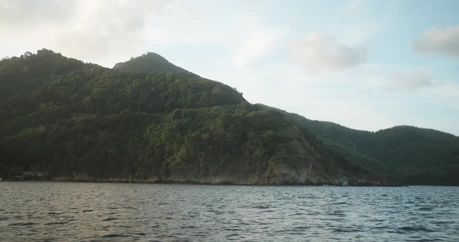 A body of water in front of a mountain on the coast