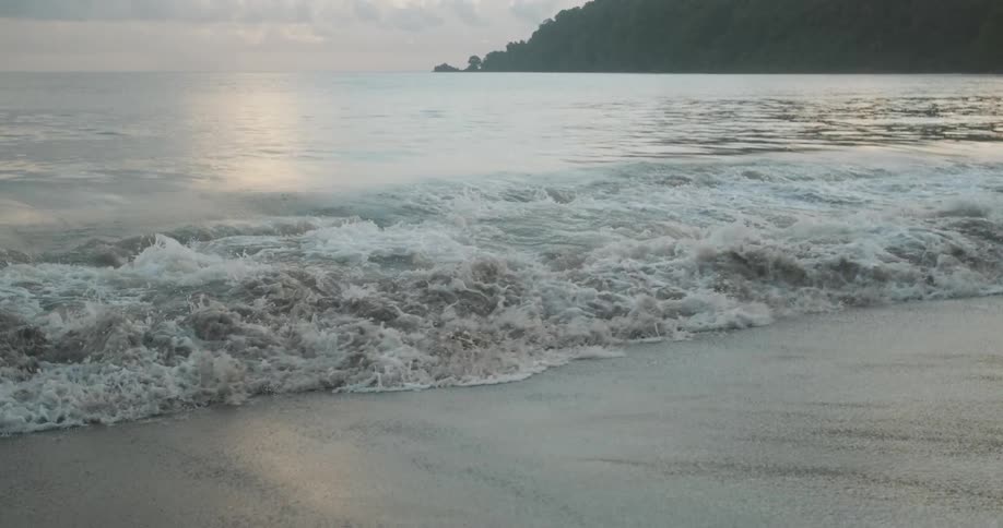 A sandy beach with waves with the sky in the background