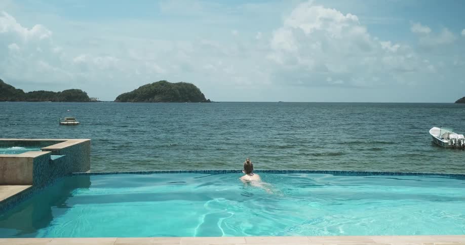 Woman swimming in an infinity pool on the ocean