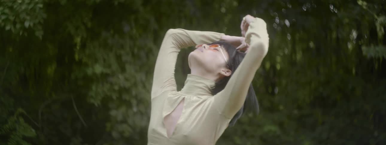 A woman is dancing outdoors in a forest area
