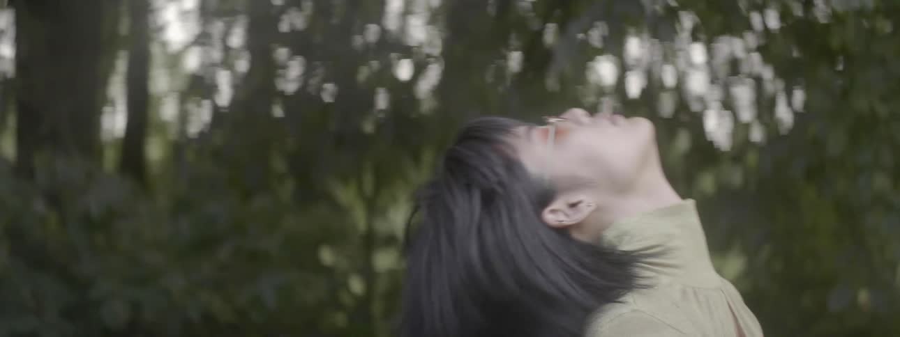 An asian woman is dancing in a forest