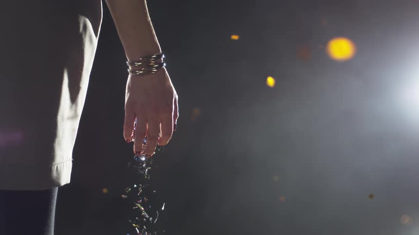 A white woman stands still as confetti falls out of her open hand