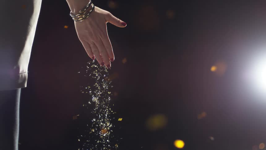 A womans hand with glitter falling from it