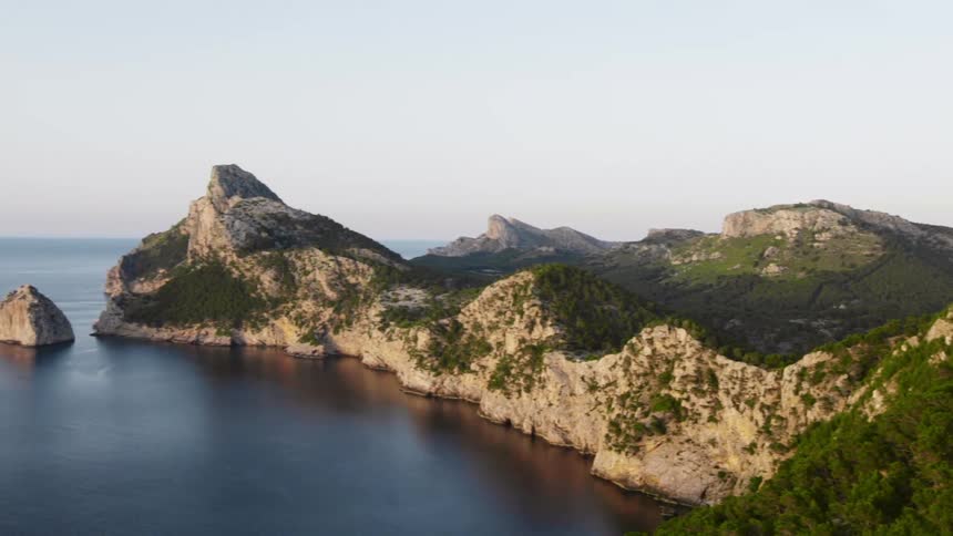 Small mountain and rocks sit near the ocean