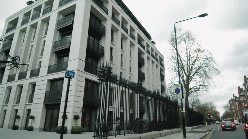 A large housing unit sits behind a fence on the corner of a city block