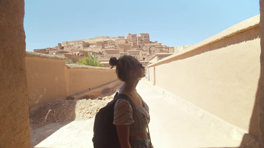 A white woman stands in a tunnel in an ancient village