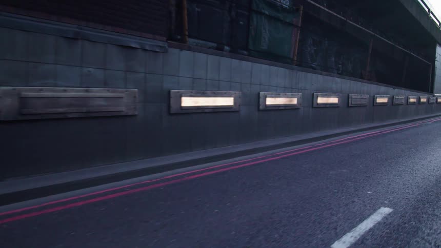Reflective markers line base of fenced pedestrian way bordering highway