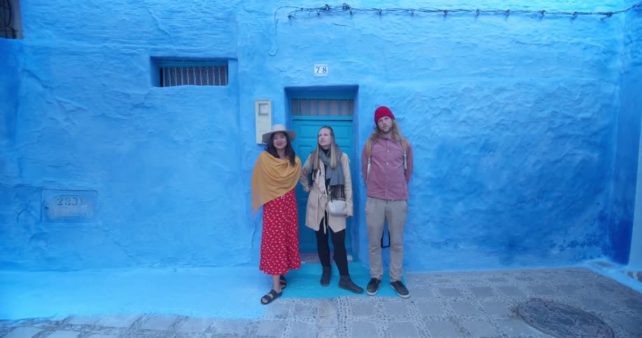 Group of people pose near door way against blue painted wall