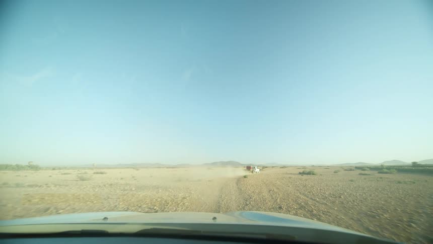 A car travels through a dirt field in a desert