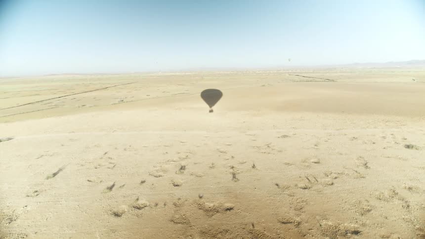 Shadow of hot air balloon traveling over desert