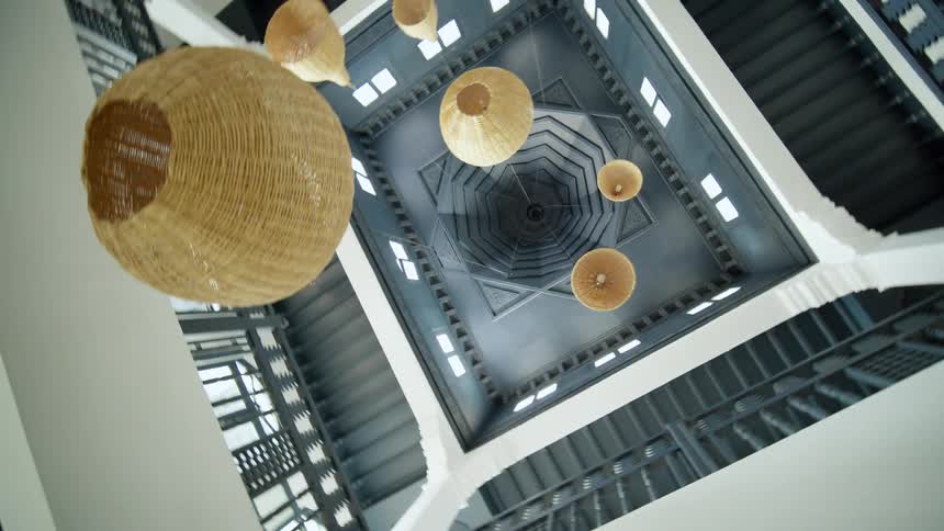 Round wicker chandeliers hang from the ceiling of a modern apartment building