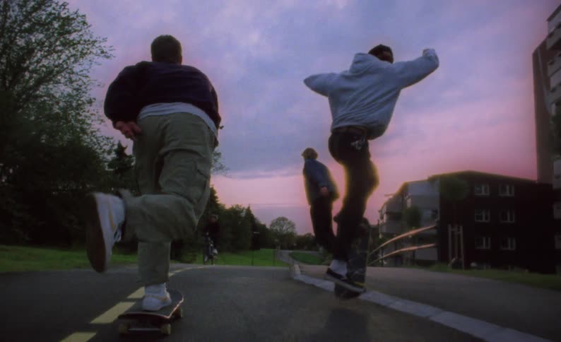 Group of teenage boys skateboarding on bike path at sunset