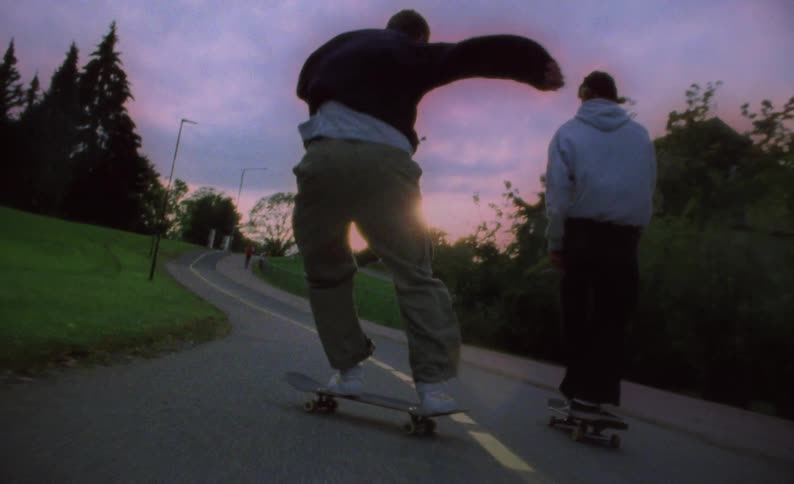 Three skateboarders riding down a park path