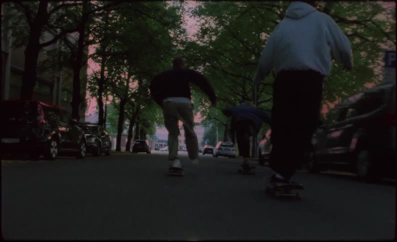 Teenagers riding skateboards down the street of a small town at day
