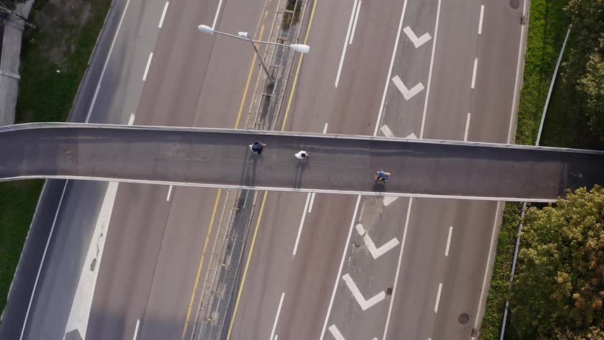 Aerial of friends skateboarding across freeway overpass