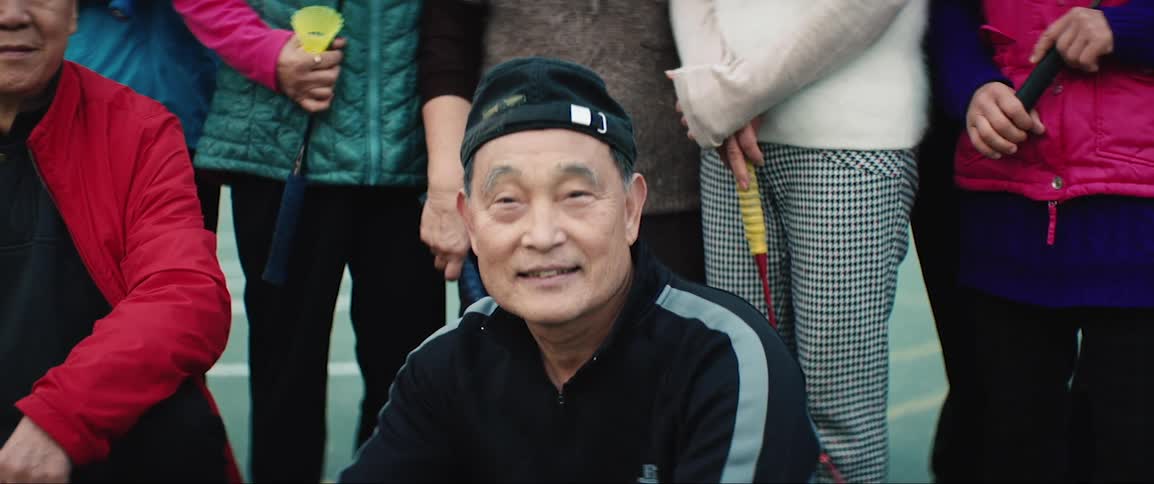 Elderly tennis players pose for the camera in the tennis court