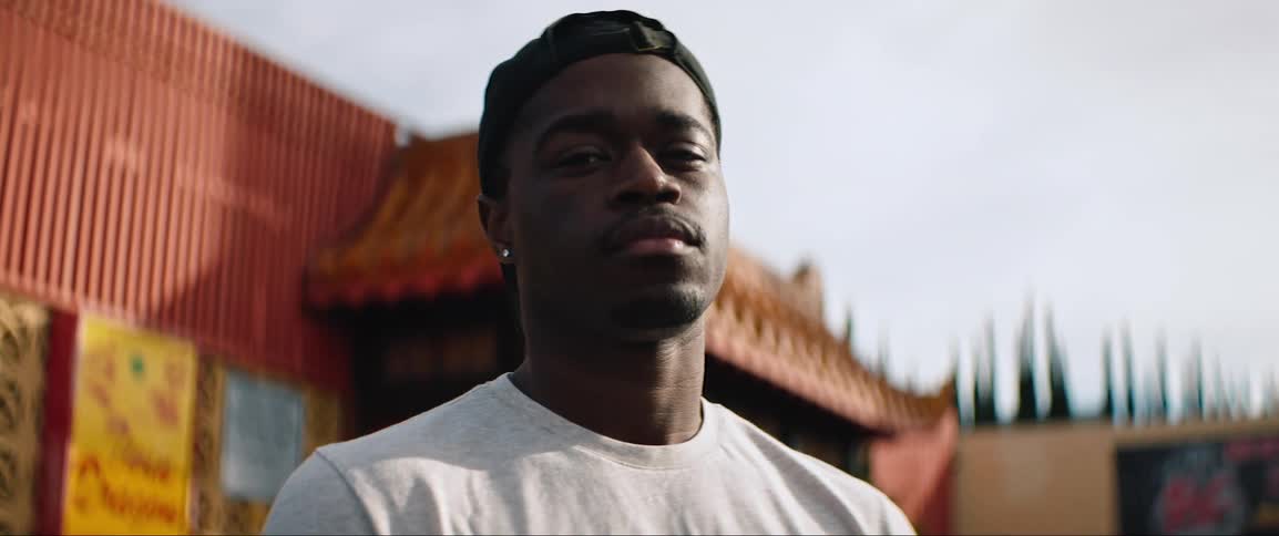 Young black man stands in front of building with asian style roof