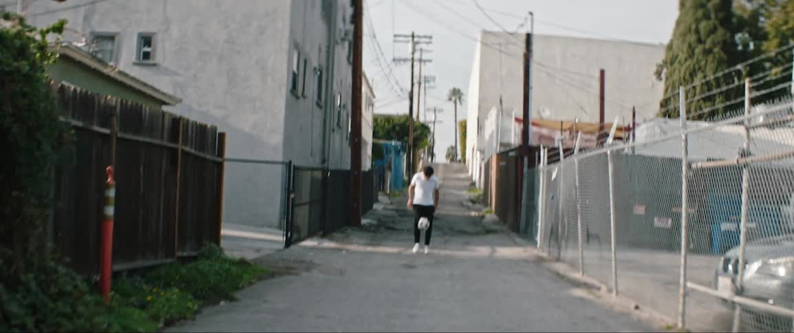 A teen kicks a soccer ball in an alley