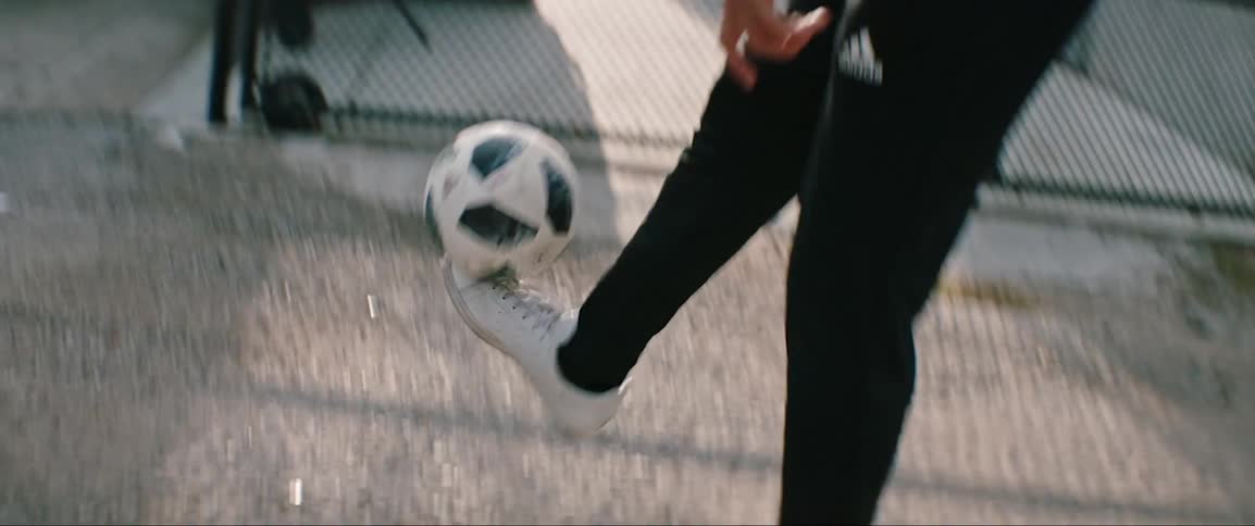Young man practices footwork with soccer ball in city alley