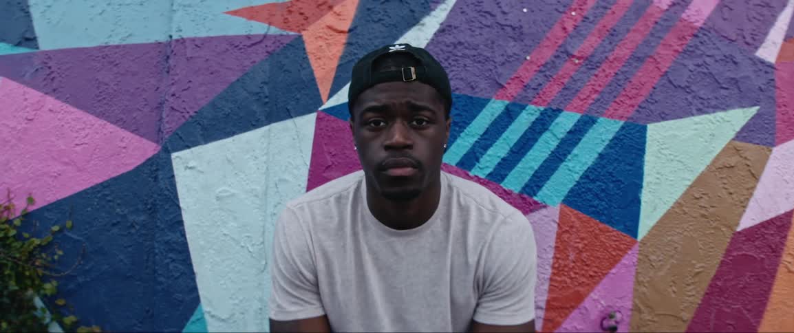 A man is sitting on the bench near the painted wall