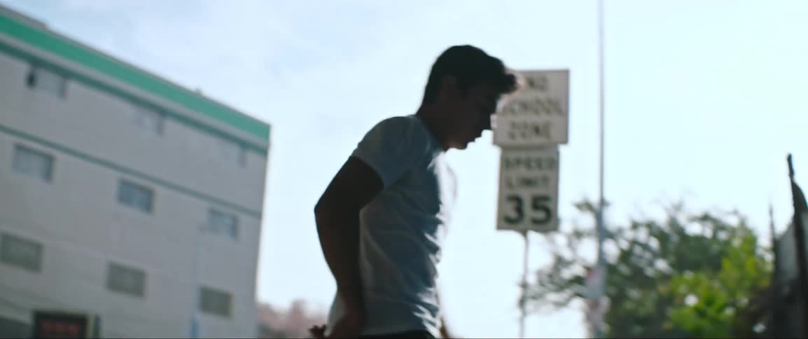 A teenager kicking a soccer ball down a city street