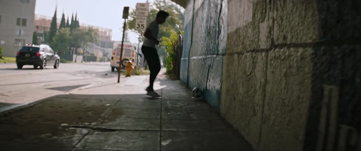 A young male kicks a soccer ball against the wall of a city tunnel