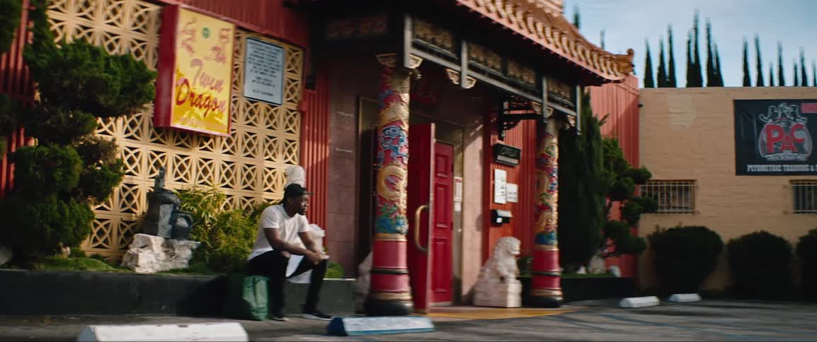 A man sits on a ledge outside a colorful chinese restaurant