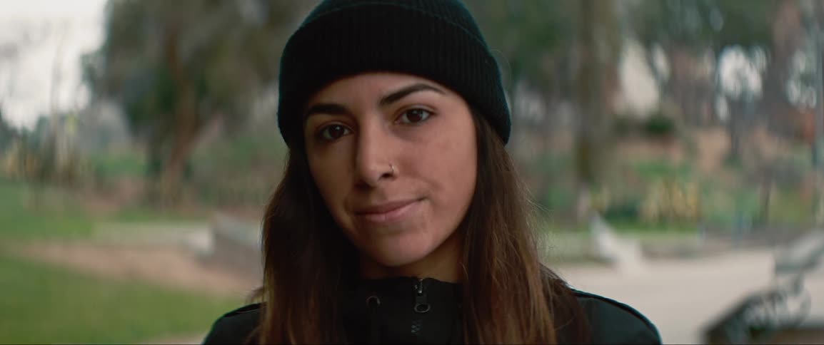 A woman standing outside looks up and smiles