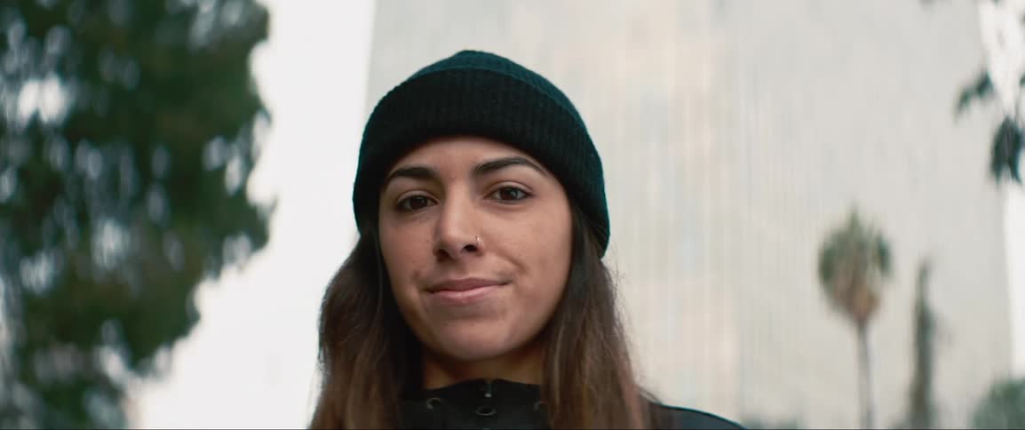 Woman wearing a black beanie stares at the camera