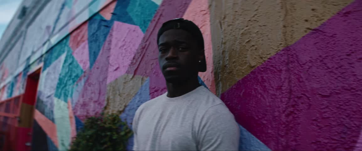 A man stands leaning against the painted wall