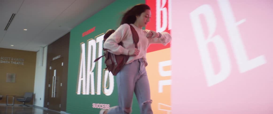 A student starts running down a hallway and checks her watch