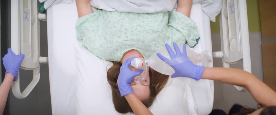 A woman is being pushed on a hospital bed down the hall