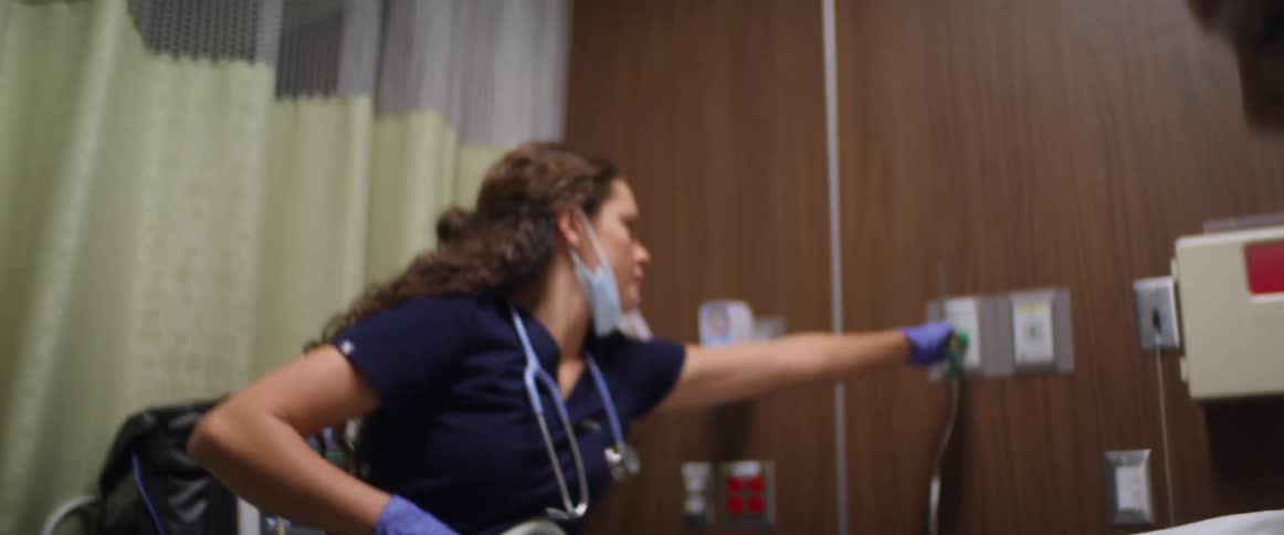 A woman laying in a hospital bed as nurses frantically work on her