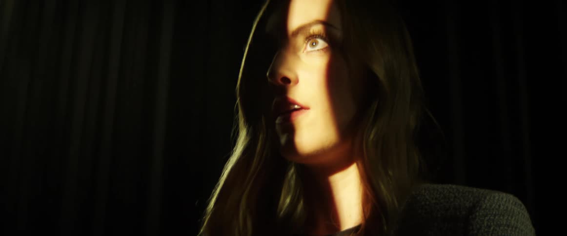 A ray of light shines on a womans face as shadow covers the rest