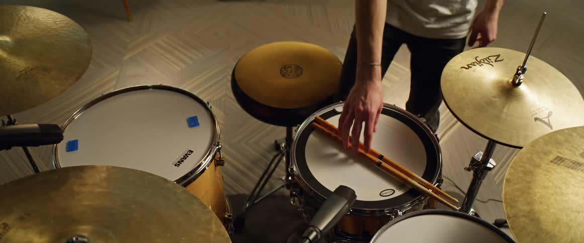 The person sits at the drums