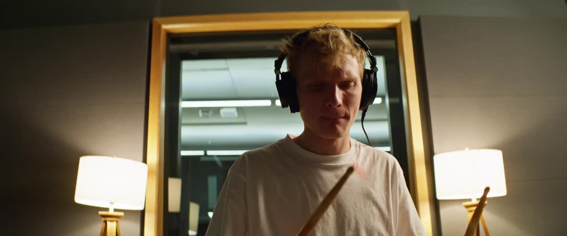 Male drummer wearing headphones plays drums