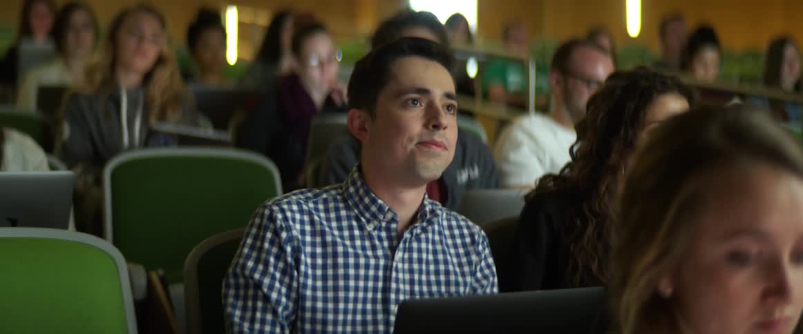 Students sitting in a lecture hall taking notes on their laptops