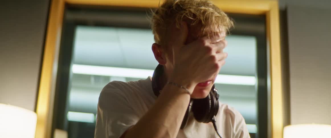 Young man removes headphones and wipes forehead