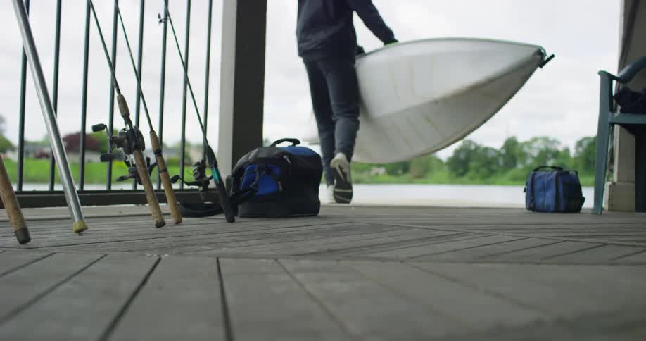 A white male carries a kayak to a lake