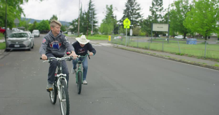 Two boys ride bicycles along the road