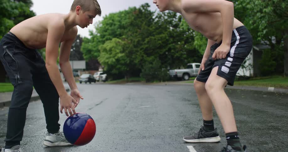 Two people are playing basketball in the street