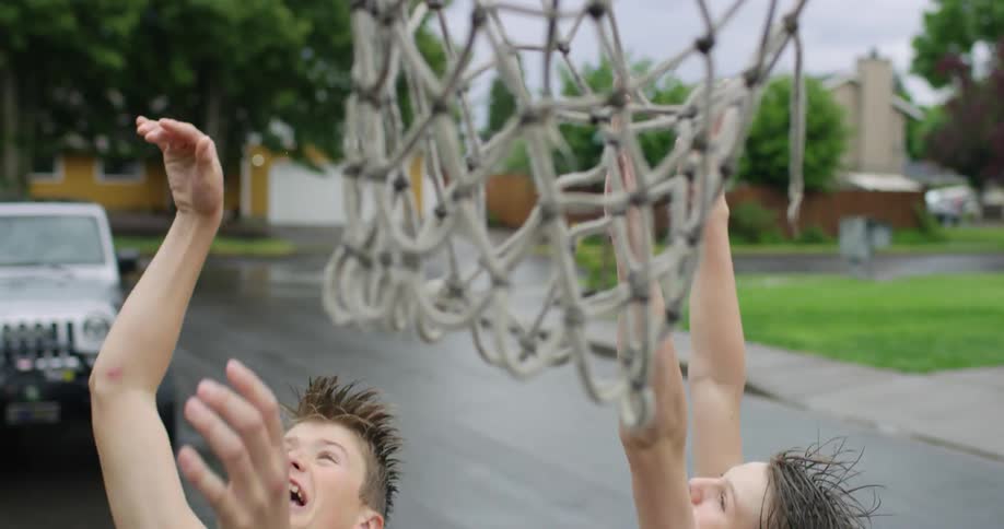 Two teenagers are playing basketball in the street